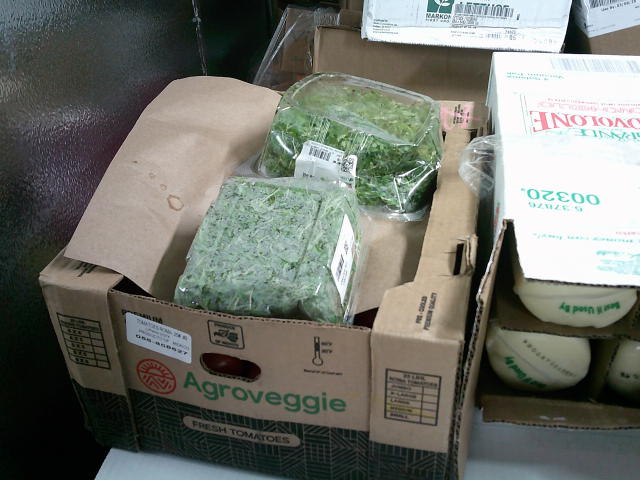 Fruit box filled with herbs next to a case of provolone.